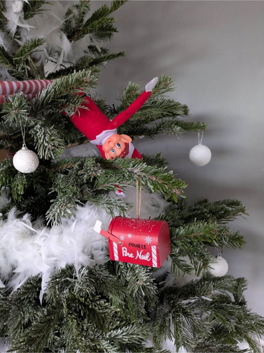 Lutin farceur accroché dans le sapin de Noël à côté d’une boîte aux lettres pour le Père Noël