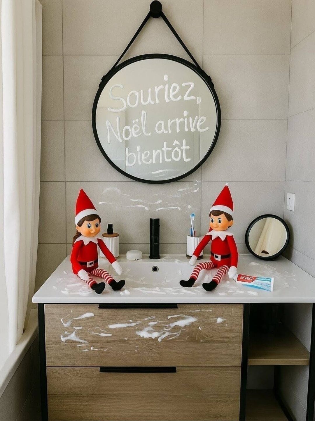 Lutins farceurs dans la salle de bain avec message “Souriez, Noël arrive bientôt” écrit sur le miroir