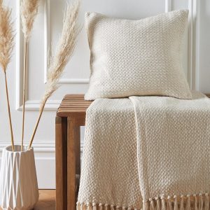 Plaid tissé en coton crème sur un banc en bois dans une déco farmhouse naturelle